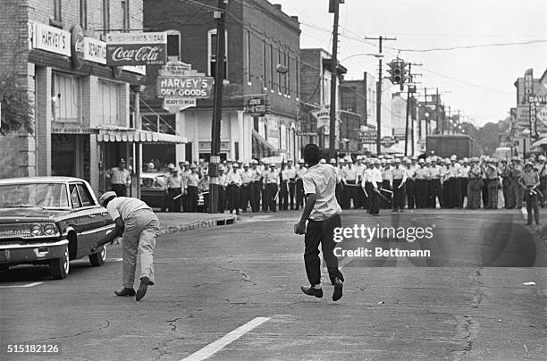 Two young black men throw rocks and bottles at Jackson policemen following a "march of mourning" for slain civil rights leader Medgar Evers. About...