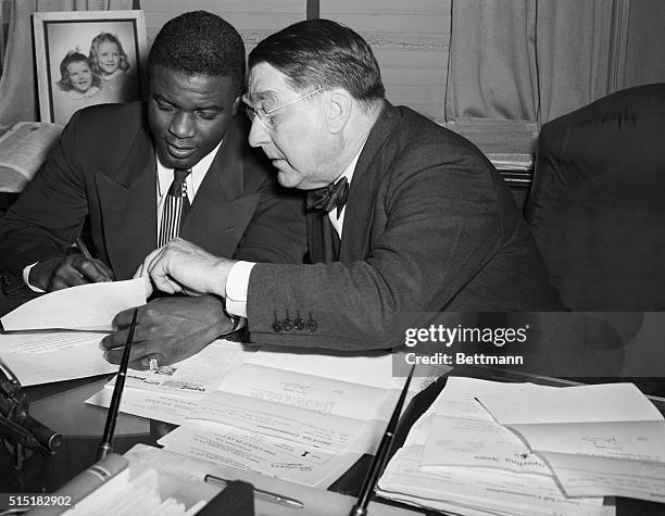 Jackie Robinson signs a contract with Brooklyn Dodger's team president Branch Rickey.