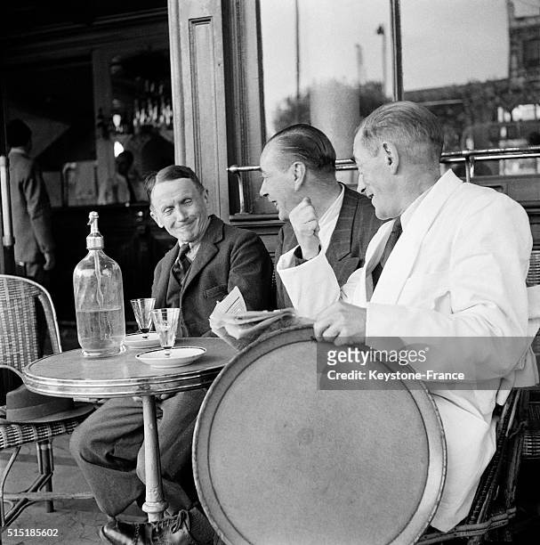 Discussion entre des clients et un serveur à une terrasse de café, à Paris, France, en 1962.