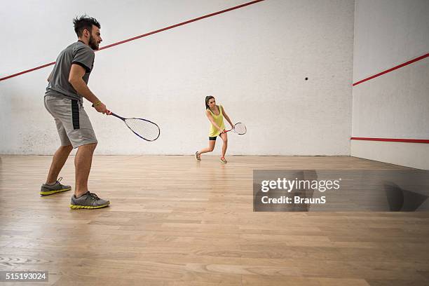young athletic couple playing squash on a court. - racket ball stock pictures, royalty-free photos & images