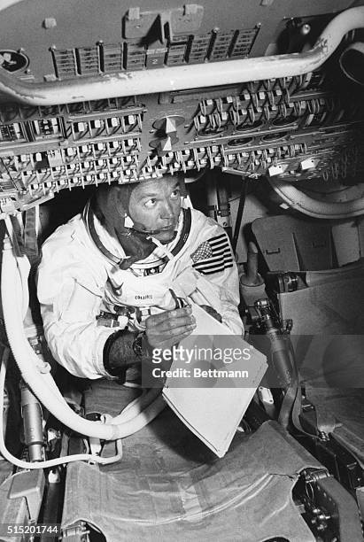 Kennedy Space Center, FL-Apollo 11 Command Module Pilot Mike Collins holds a manual as he checks switches during practice in a command module...