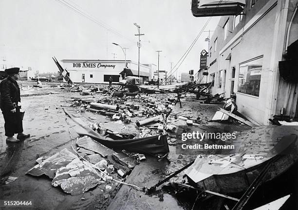 Crescent City, CA- Unidentified man stands amid debris-ridden city where martial law was declared after tremendous tidal waves from the Anchorage,...