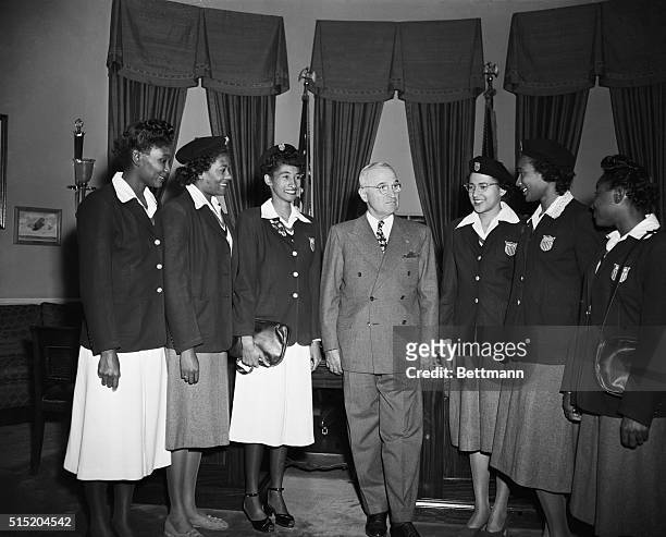President Harry S. Truman stands with a group of African American Olympic athletes in the Oval Office for the annual football game between Tennessee...
