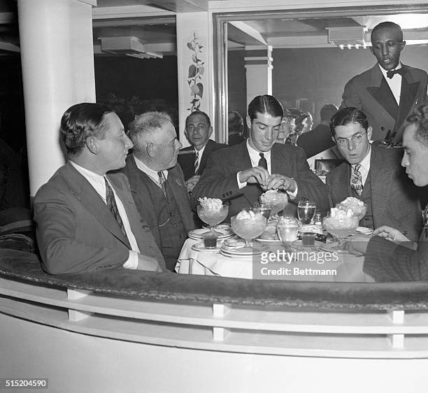 Attacking his food with relish after the opening game of the World Series, Joe DiMaggio, NY Yankees star, is shown with his father and his brother,...