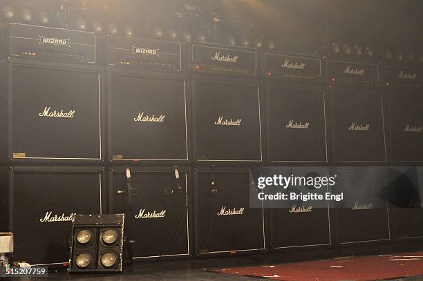 Row of six Marshall stack amplifiers and speaker cabs, including two Wizard amplifier heads, miked up and under stage lighting, on stage at a music...