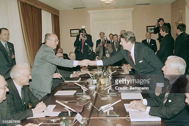 Soviet General Secretary Mikhail Gorbachev and U.S. President Ronald Reagan reach across the conference table to shake hands as the third summit...