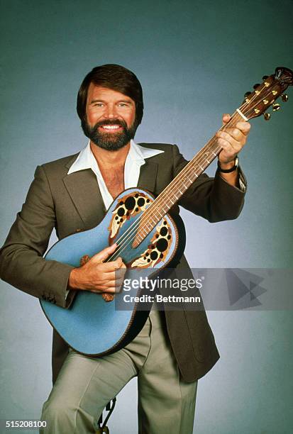 Publicity handout of bearded Country/Western musician Glen Campbell posing with a guitar.