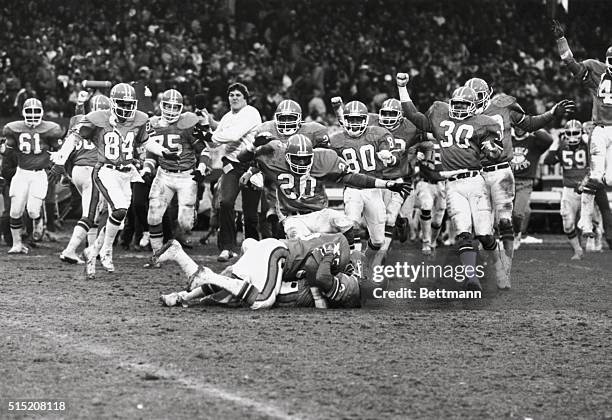 Cleveland, Ohio: Rick Dennison of Denver jumps kicker Rich Karlis after Karlis kicked a field goal in an overtime game with Cleveland to win the AFC...