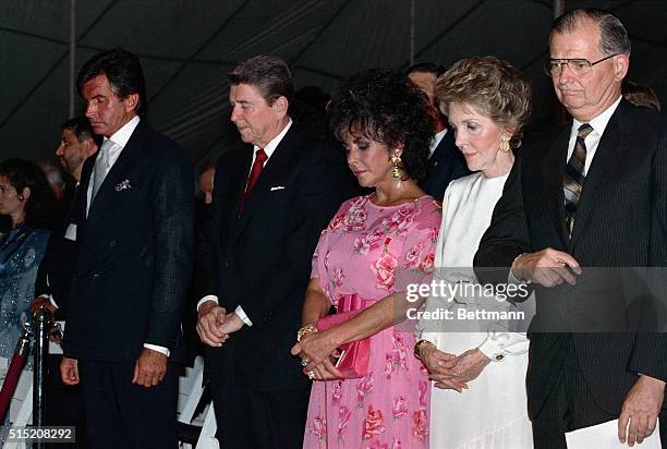 Washington, DC- President Reagan and Liz Taylor bow their heads during a moment of silence for those who have died of AIDS during a fund raising...