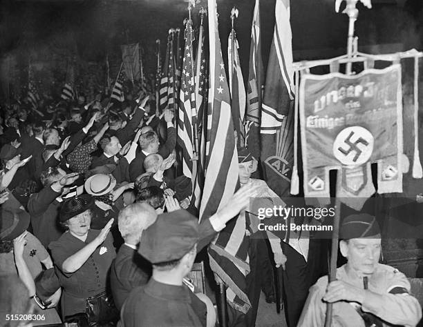 Snapping into the regulation Nazi salute, Bund members hail the swastika banner as it is paraded in Madison Square Garden during opening ceremonies...
