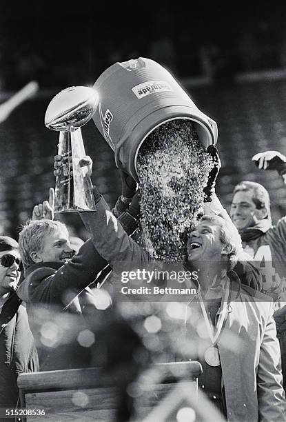 East Rutherford, N.J.: Bill Parcells, N.Y. Giants' head coach, looks up as quarterback Phil Simms, the Super Bowl's MVP, dumps a bucket filled with...