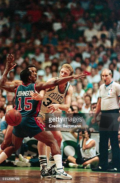 Celtics' Larry Bird passes around the back of Pistons' Vinnie Johnson as he is cornered by Johnson and Adrian Dantley during second quarter action in...