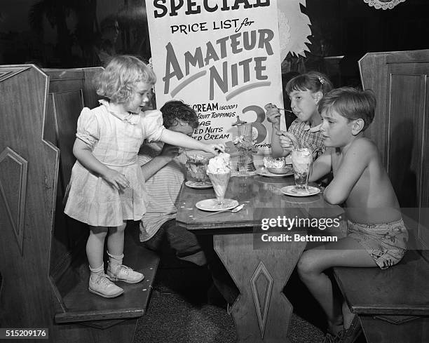 Hollywood, CA- ORIGINAL CAPTION READS: Three youthful amatures watch Kristian Helmer, 3 reach for the cherry atop her sundae. Left to right: Kristian...