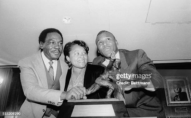 Heisman Trophy winner Barry Sanders and his parents stand by the trophy he won as the outstanding college football player of 1988 during a ceremony...