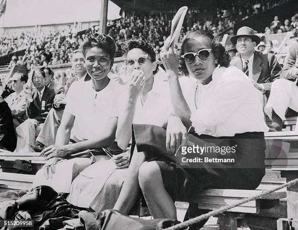Three U.S. Olympic athletes watch other Olympic stars as they take it easy, in the spectator stands at Wembley Stadium, London, July 31st 1948. Left...