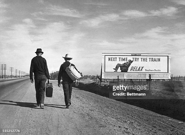 Two Dust Bowl refugees walk along a highway towards Los Angeles. Passing by a billboard imploring them "Next Time Try the Train - Relax".