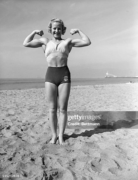 Relna Brewer shown in muscle pose with arms flexed. Full length frontal photograph.