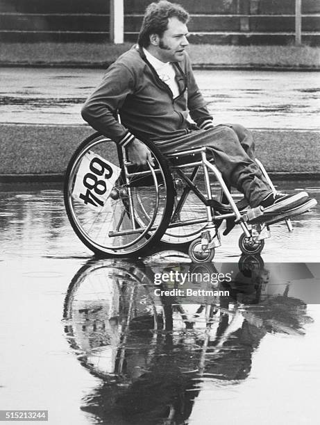 New Zealand athlete Dennis Miller competing in wet conditions in a wheelchair race at the 21st International Stoke Mandeville Games, later known as...