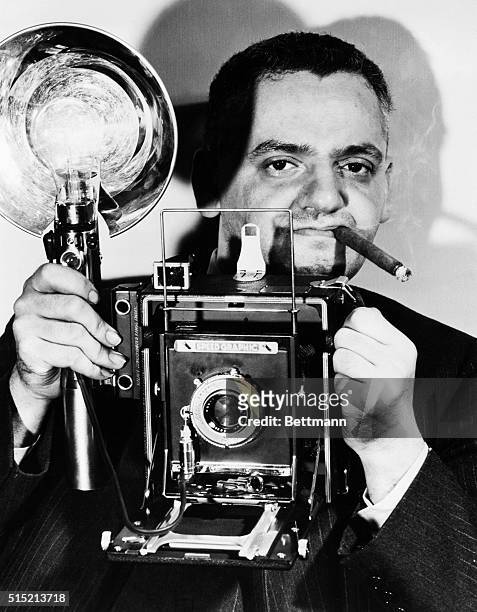 Arthur Fellig, known as "Weegee," chomps his cigar and holds his Speed Graphic camera. A photographer of New York crime, disasters, and urban...