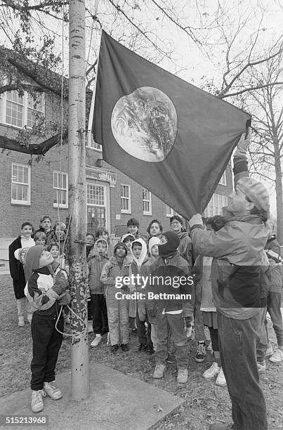 Students from The College School of Webster Groves watch as designer David Fischer and his son Jesse raise the Earth Day flag. Fischer designed the...