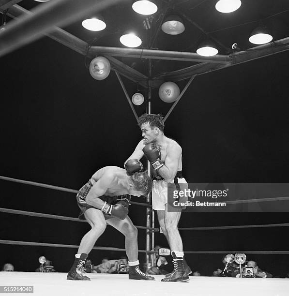 Jersey City, NJ - Tony Zale ducks under a hard right thrown by Marcel Cerdan in eighth round of their Middleweight Championship bout at Roosevelt...