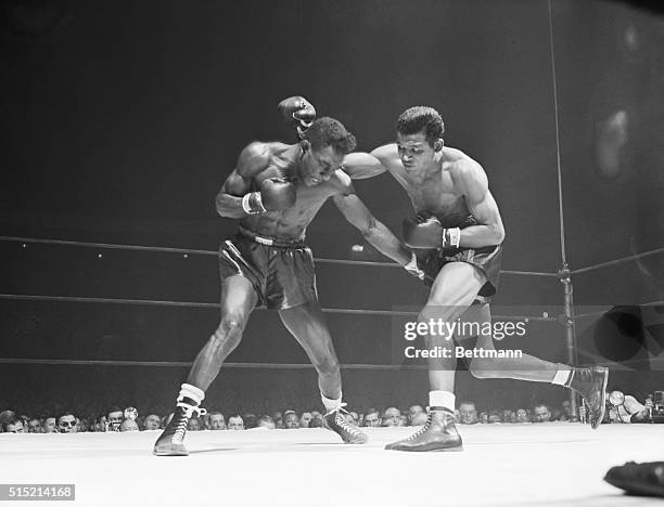 New York, NY- Tommy Bell of Youngstown, Ohio ducks just in time as Ray "Sugar" Robinson of New York rolls a right over his shoulder in a 15-round...
