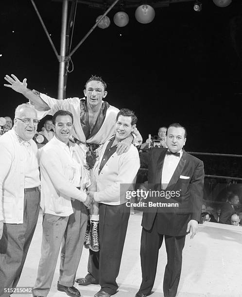 New York, NY: Winner and new middleweight champion Carmen Basilio, held aloft in the ring by manager Joe Nitro , trainer Angelo Dundee and manager...