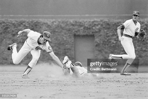 Chicago, IL-A Philadelphia Phillies player is shown sliding into a base as surrounding Chicago Cubs attempt to tag him out.