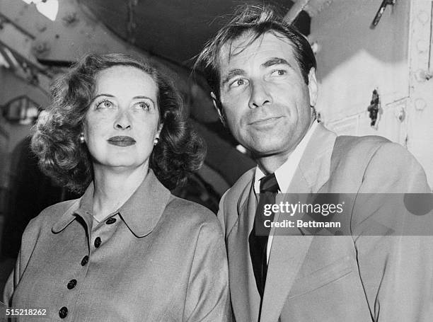 New York, New York- Screen actress Bette Davis and her slightly wind-blown husband, actor Gary Merrill, arrive in New York aboard the Queen...