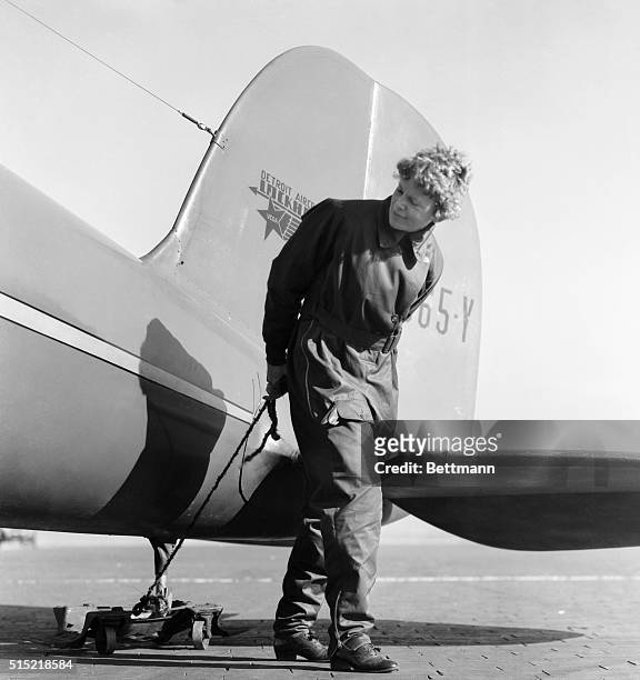 Amelia Earhart, , first woman to crosss the Atlantic Ocean in an airplane. She stands impishly near the rear of her aircraft. Undated photograph.