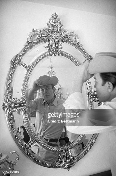 Fully attired in western garb, singer Jimmy Dean makes a final check in the mirror.