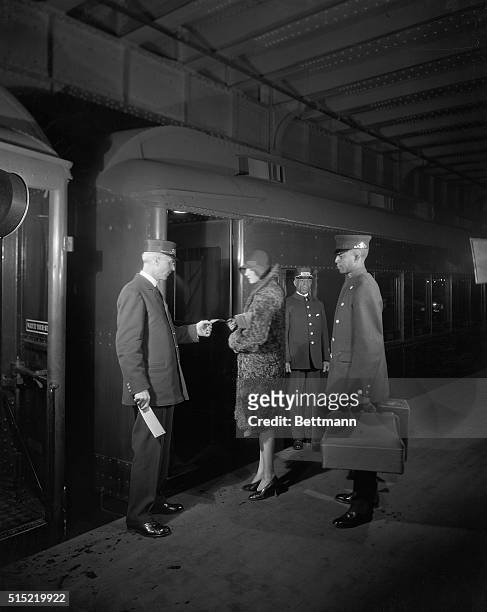 Lady about to board train, with porter, trainman and conductor. Photograph, ca. 1940s.