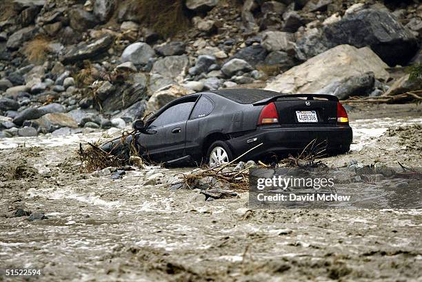 Car lies where it was swept away when its driver tried to cross the swollen waters of Lytle Creek on Lytle Creek Road, the only way out for the rural...