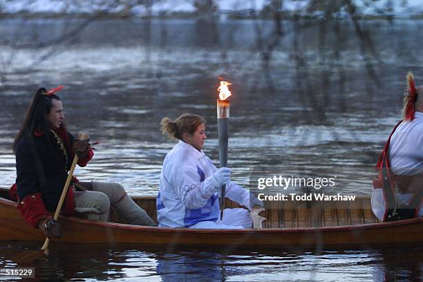 Torchbearer Casey Farties, assisted by members of the Abernaki Tribe, transports the Olympic Flame across the Connecticut River during the 2002 Salt...