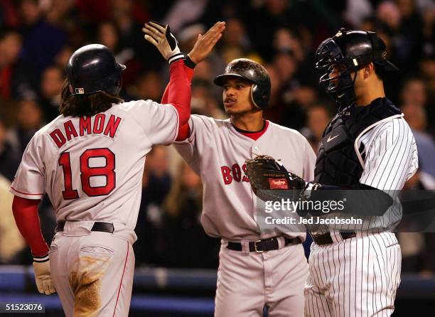 Catcher Jorge Posada of the New York Yankees looks on as Johnny Damon of the Boston Red Sox is congratulated by teammate Orlando Cabrera after...