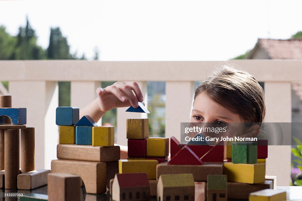 Young girl building a town with wooden bricks