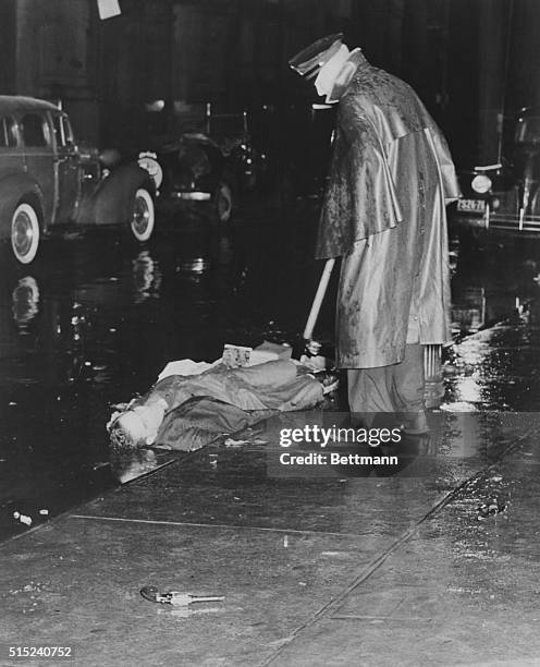 Slain on the East Side. New York, New York: A policeman looks at the body of Louis Riggiona, found dead in the gutter of Mulberry St., New York's...