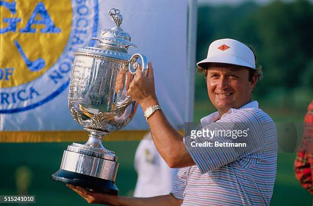 Golfer Ray Floyd smiles as he holds the PGA Championship Trophy.