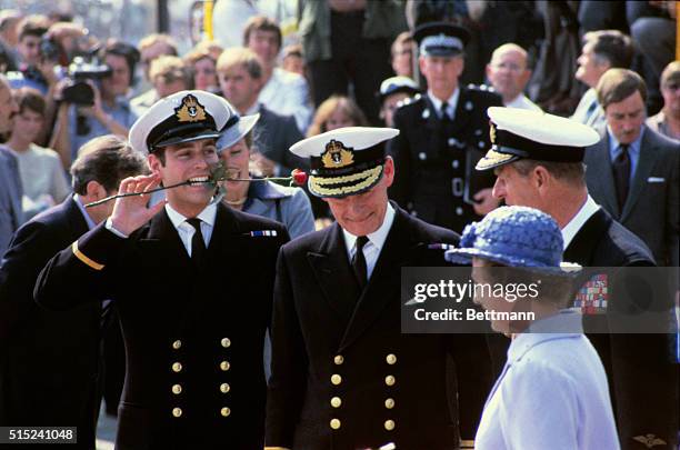 Prince Andrew holds a rose in his mouth, as he and his mother and father, Queen Elizabeth and Prince Philip return from the Falklands on board the...
