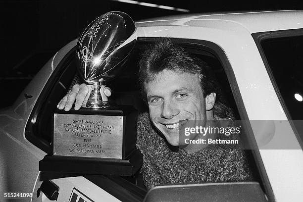 Joe Montana, quarterback of the world champion San Francisco 49ers, flashes Sport Magazine's MVP trophy given him for his super Super Bowl...