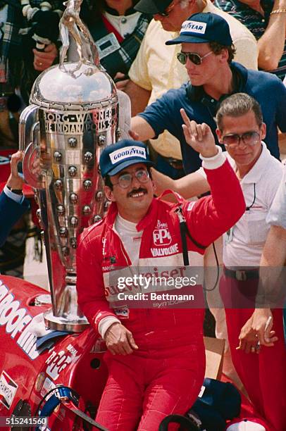 Bobby Rahal puts his finger in the air, signifying victory in the Indianapolis 500. Behind Rahal is the Borg-Warner trophy. Rahal had record average...