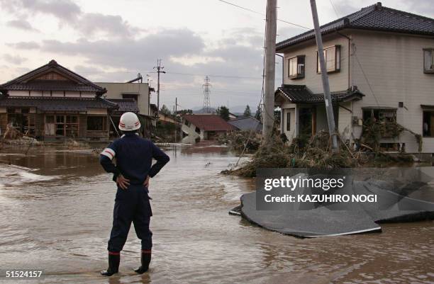 Rescuer looks at the damages of a flooded area hit by typhoon Tokage in Izushi town, Hyogo Prefecture, 21 October 2004. Japan was searching for...