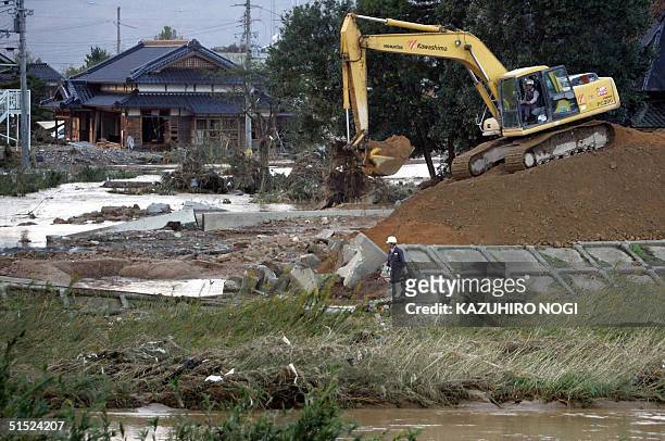 Japanese workers are on duty at a collapsed bank of a river in Izushi town, hit by Typhoon Tokage in Hyogo Prefecture, 21 October 2004. Japan was...
