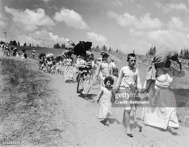 Large bundles of personal possessions are carried on the head of Arab women and children begin a three mile hike through no man's land to the Arab...