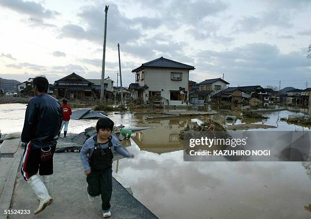 People walk around flooded streets in Izushi, Hyogo Prefecture, 21 October 2004. Japan was searching for survivors after the country's deadliest...