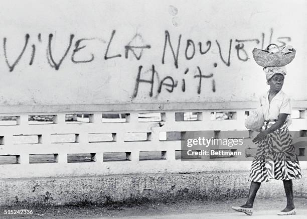 Leogane, Haiti: A Haitian woman walks by a sign on the market here, February 11, which reads "long live new Haiti." The sign was painted on the wall...