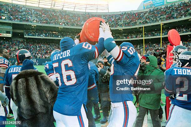 New York Giants linbackers Lawrence Taylor and Gary Reasons get ready to give coach Bill Parcells a Gatorade shower as they clinched the NFC East...