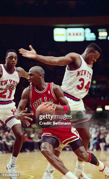 Though grounded, Air Jordan, of the Chicago Bulls, eludes two New York Knicks, Gerald Wilkins and Charles Oakley , as he heads for the basket during...