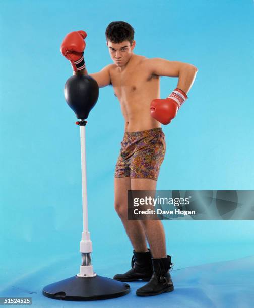 Pop singer Robbie Williams, a member of boy band Take That, posing with a punchbag and wearing boxing gloves with his boxer shorts and boots, as worn...