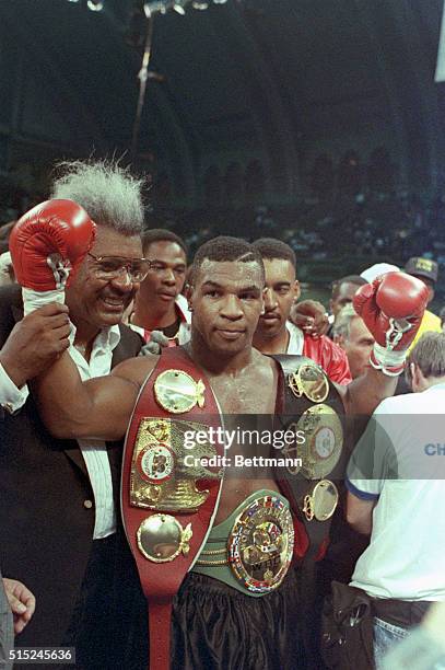Mike Tyson celebrates his victory over Carl Williams as boxing promoter Don King Walks by his side.
